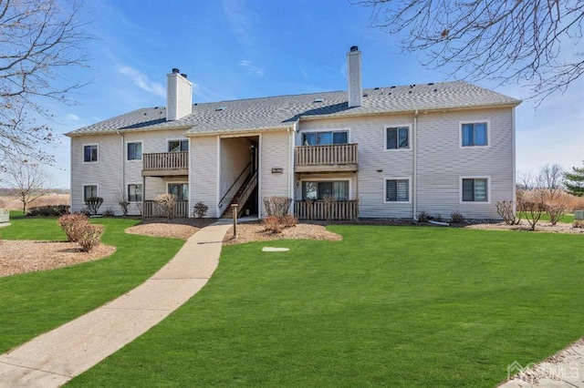 rear view of house featuring a balcony and a yard