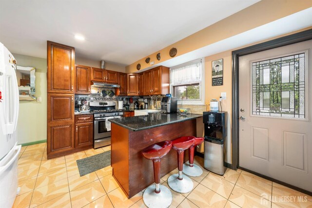 1814 Hamilton Blvd, South Plainfield, NJ 07080 - kitchen featuring gas stove, under cabinet range hood, freestanding refrigerator, a peninsula, and tasteful backsplash
