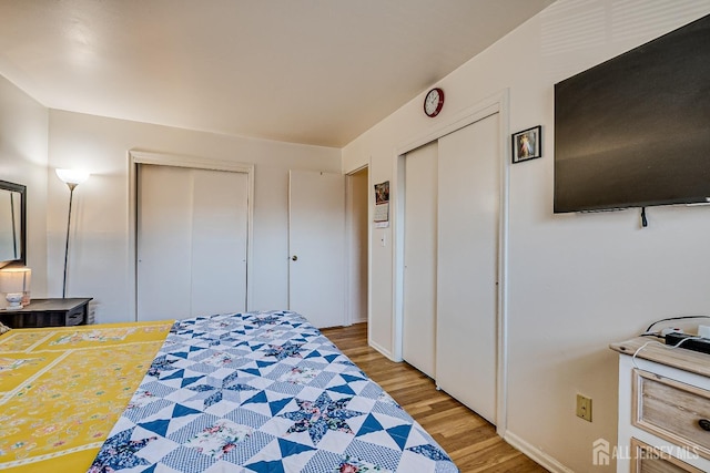 bedroom featuring multiple closets and light wood-style floors