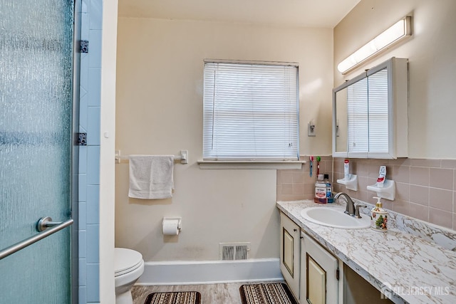 full bathroom with a stall shower, vanity, toilet, baseboards, and healthy amount of natural light