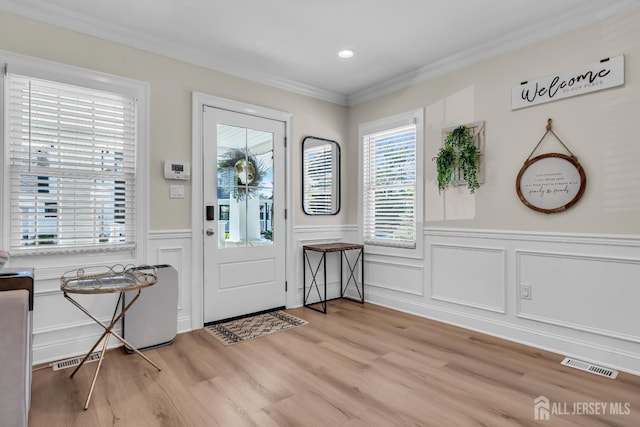 entryway with light wood-style floors, crown molding, wainscoting, a decorative wall, and recessed lighting