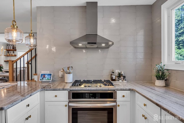 kitchen with stainless steel appliances, wall chimney exhaust hood, decorative backsplash, and plenty of natural light