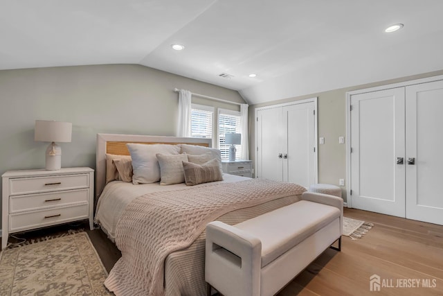 bedroom featuring multiple closets, lofted ceiling, recessed lighting, and wood finished floors