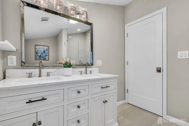 full bathroom with double vanity, baseboards, and a stall shower