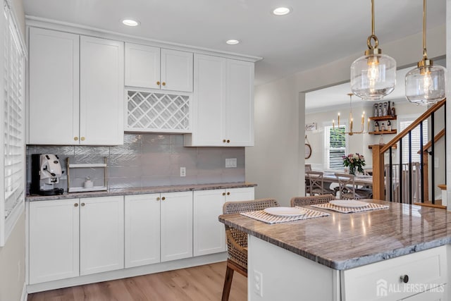 1307 Camp Ave, Ocean, NJ 07712 - kitchen with light wood-type flooring, dark stone counters, white cabinets, recessed lighting, and tasteful backsplash