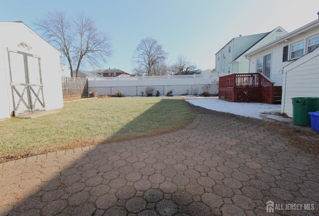 view of yard with a wooden deck, a patio area, and a storage unit