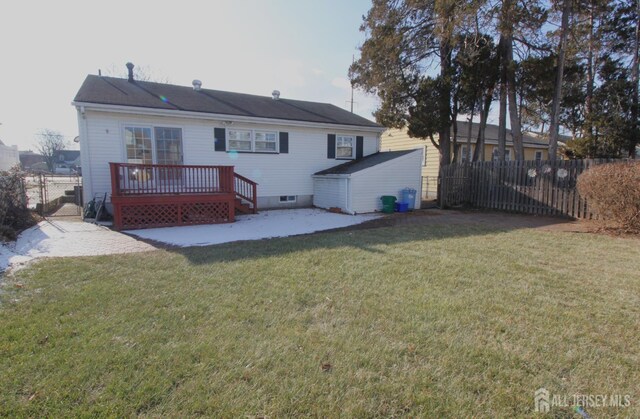 rear view of house featuring a patio area, a wooden deck, and a lawn