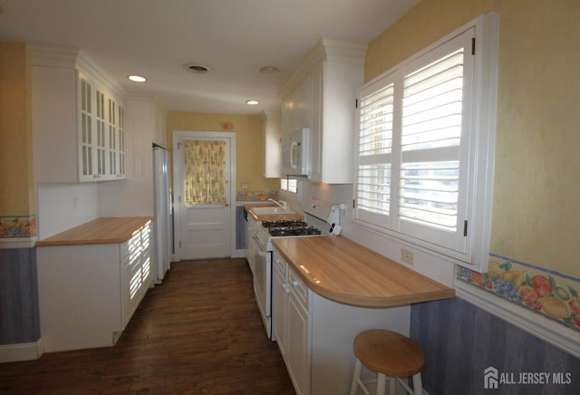 kitchen featuring a healthy amount of sunlight, sink, white appliances, and white cabinetry