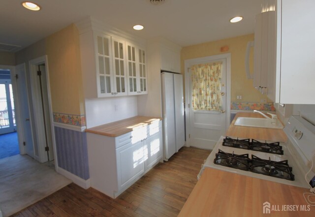 kitchen featuring white cabinets, sink, white appliances, and hardwood / wood-style flooring