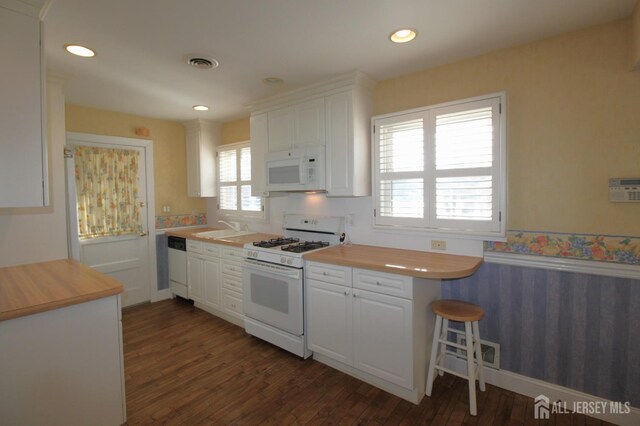 kitchen featuring dark hardwood / wood-style floors, white cabinets, and white appliances