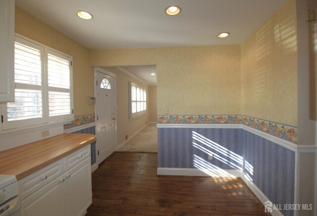 kitchen featuring dark wood-type flooring, plenty of natural light, white cabinets, and butcher block counters