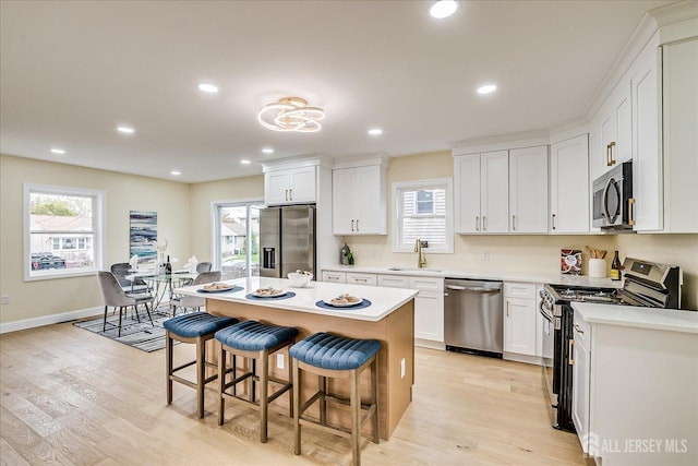 24 Savoy St, Colonia, NJ 07067 - kitchen featuring appliances with stainless steel finishes, a sink, a kitchen bar, light wood-style flooring, and white cabinets