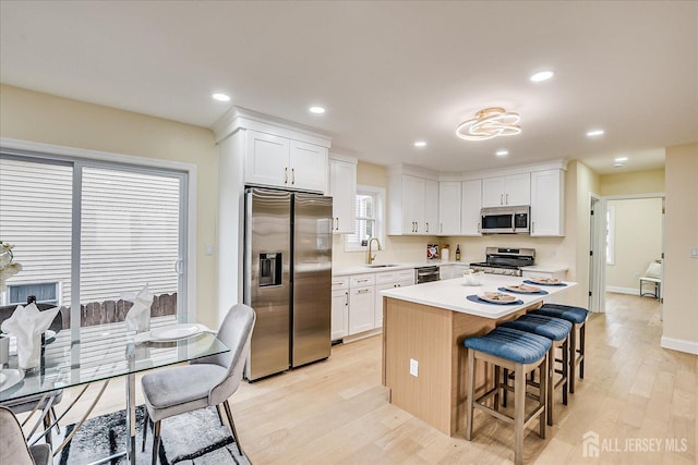 24 Savoy St, Colonia, NJ 07067 - kitchen featuring stainless steel appliances, a sink, a kitchen bar, white cabinetry, and light wood-style floors