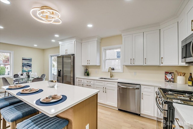 24 Savoy St, Colonia, NJ 07067 - kitchen with appliances with stainless steel finishes, a sink, a kitchen breakfast bar, light wood-style floors, and light countertops
