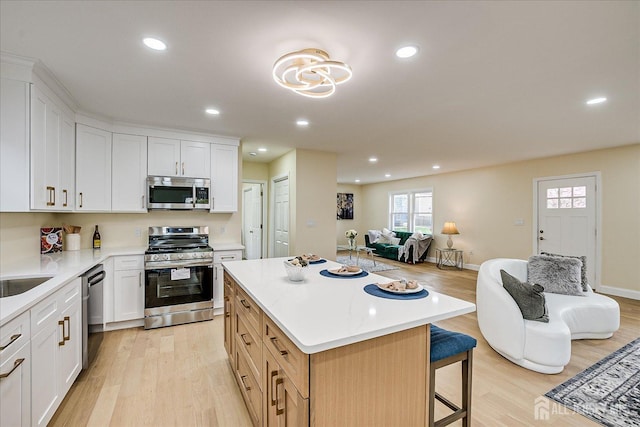 24 Savoy St, Colonia, NJ 07067 - kitchen featuring stainless steel appliances, light wood finished floors, open floor plan, recessed lighting, and a breakfast bar