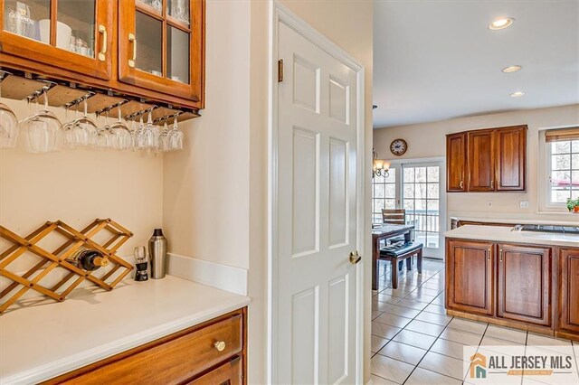 27 Revere Ct, West Windsor, NJ 08550 - kitchen featuring brown cabinets, light tile patterned flooring, light countertops, glass insert cabinets, and recessed lighting