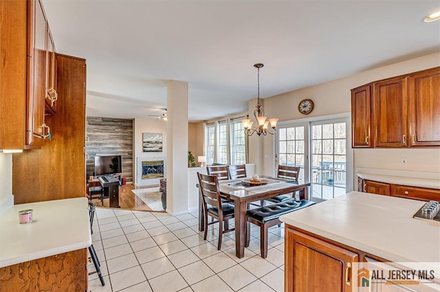27 Revere Ct, West Windsor, NJ 08550 - dining space featuring a glass covered fireplace, light tile patterned flooring, ceiling fan, a chandelier, and baseboards