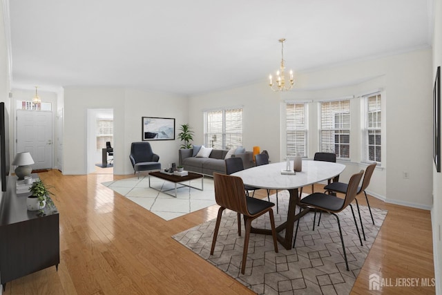 dining area featuring a notable chandelier, ornamental molding, and light wood-type flooring