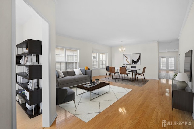 living room featuring hardwood / wood-style flooring, ornamental molding, a wealth of natural light, and a chandelier