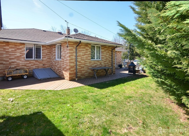 back of house featuring a wooden deck, a yard, and brick siding