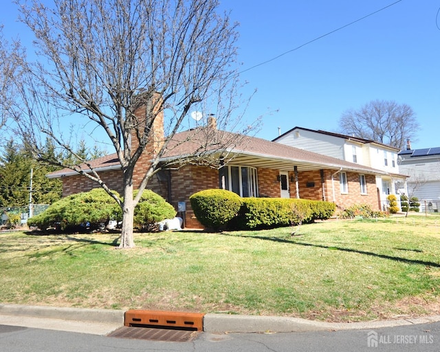 view of front facade with a front lawn, brick siding, and a chimney