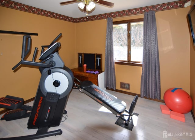 workout room with wood finished floors, visible vents, ceiling fan, and baseboards