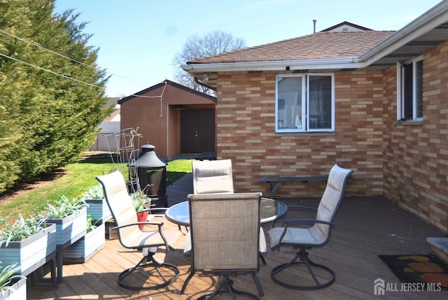 deck featuring a storage unit, outdoor dining space, and an outdoor structure