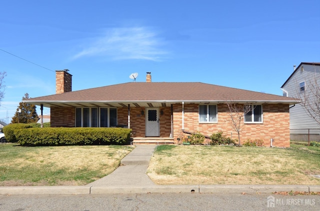 ranch-style home with a chimney, covered porch, brick siding, and a front lawn