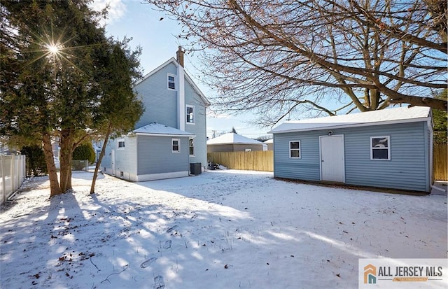 snow covered property with an outbuilding and central AC