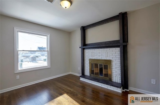 unfurnished living room with a brick fireplace and dark wood-type flooring