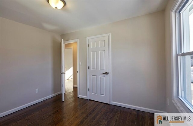 unfurnished bedroom with dark hardwood / wood-style floors and a closet