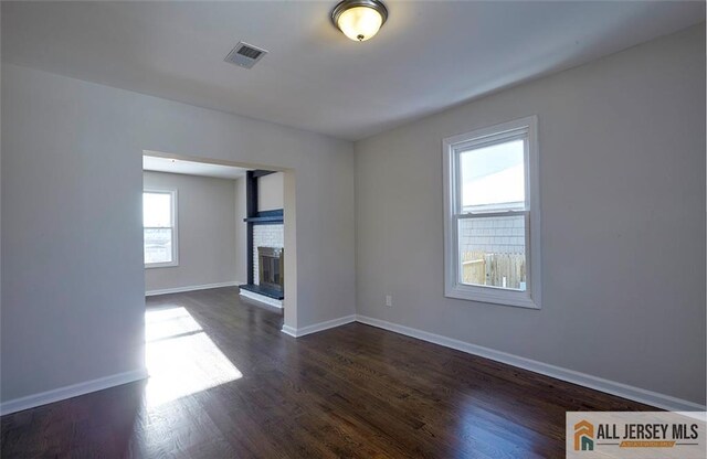 unfurnished room with dark hardwood / wood-style flooring and a fireplace