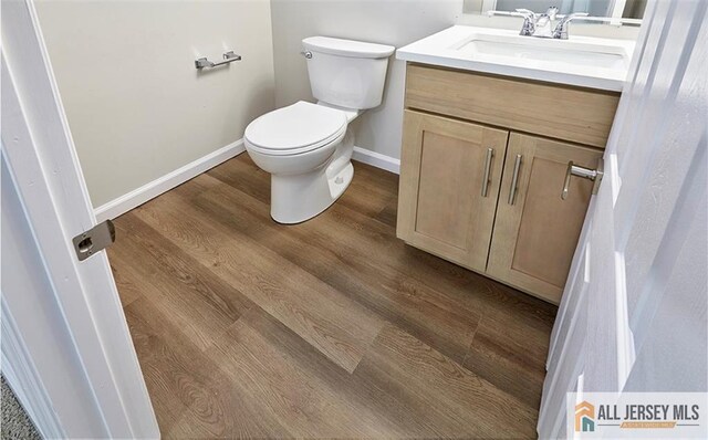 bathroom with vanity, toilet, and wood-type flooring