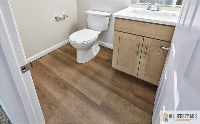 bathroom with hardwood / wood-style flooring, vanity, and toilet