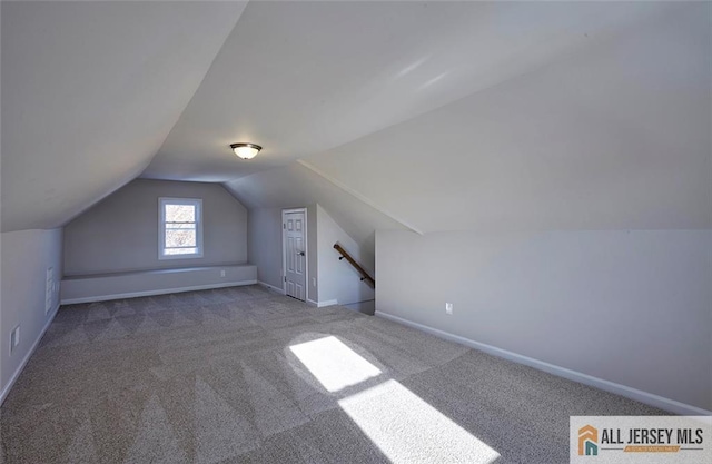 additional living space with vaulted ceiling and carpet flooring