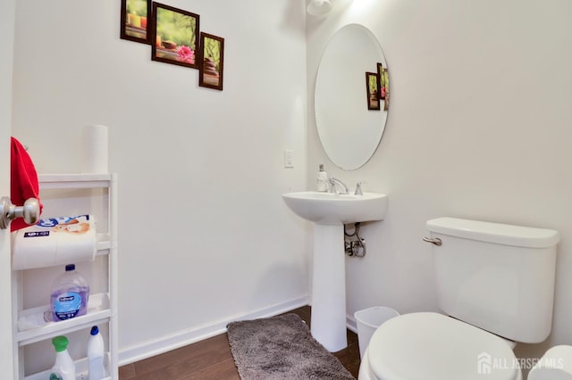 bathroom featuring toilet, wood finished floors, and baseboards