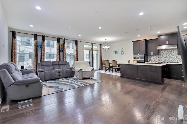 living area featuring a chandelier, dark wood-type flooring, and recessed lighting