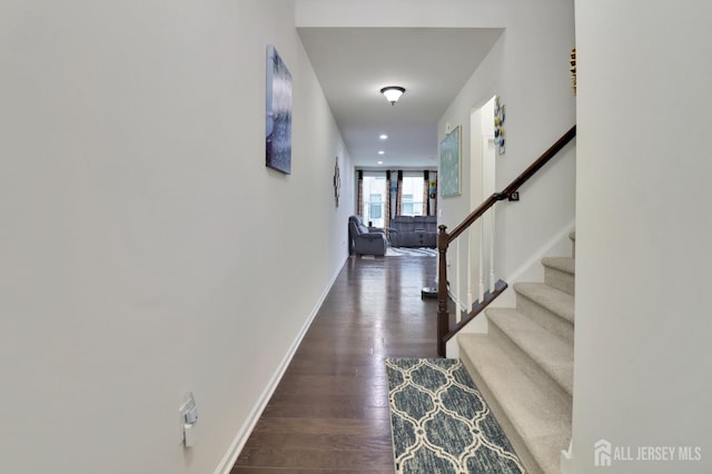 hallway featuring wood finished floors, stairs, and baseboards