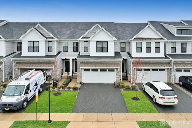 view of property with board and batten siding, a garage, driveway, stone siding, and a front lawn