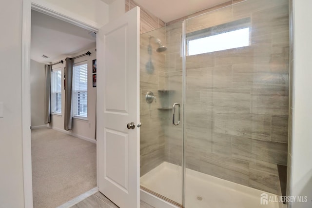 bathroom featuring a stall shower, plenty of natural light, and baseboards
