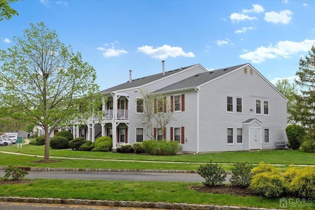 view of front of property with a balcony and a front lawn