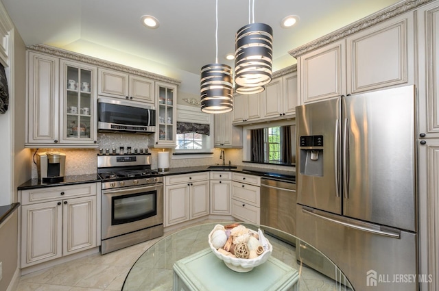 kitchen featuring a sink, appliances with stainless steel finishes, tasteful backsplash, and cream cabinetry
