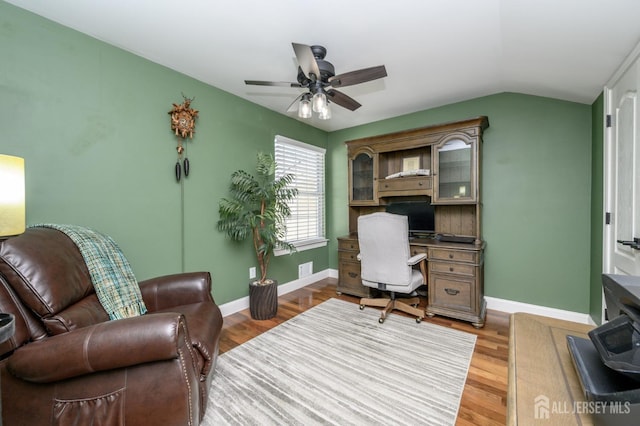 office with visible vents, a ceiling fan, baseboards, light wood-type flooring, and vaulted ceiling