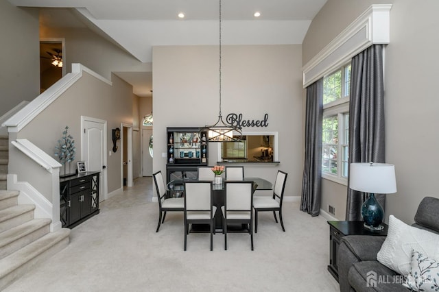 dining area with light colored carpet, stairs, baseboards, a high ceiling, and recessed lighting