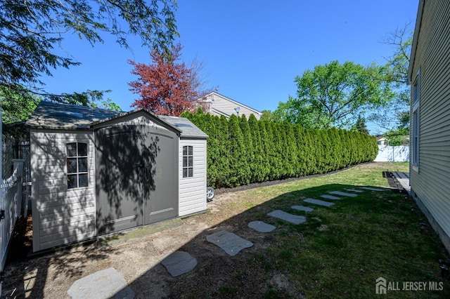 view of yard with fence, an outdoor structure, and a shed