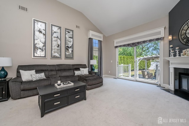 living room with carpet floors, a glass covered fireplace, baseboards, vaulted ceiling, and visible vents