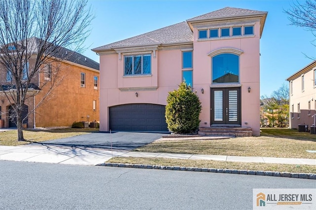 view of front facade with aphalt driveway, a front yard, stucco siding, french doors, and a garage