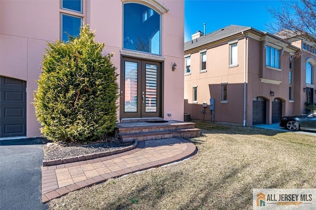 view of exterior entry featuring stucco siding, french doors, and driveway