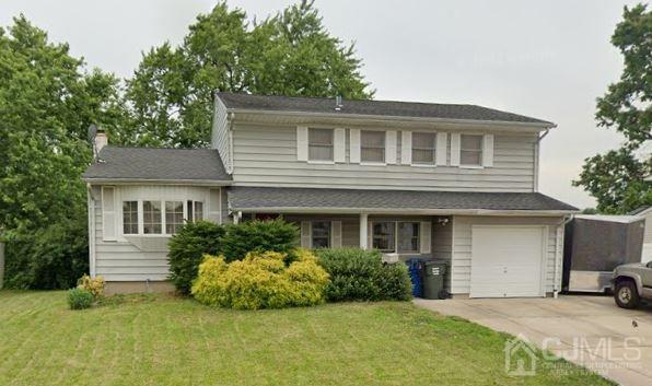 view of front of property with a front yard, concrete driveway, and an attached garage