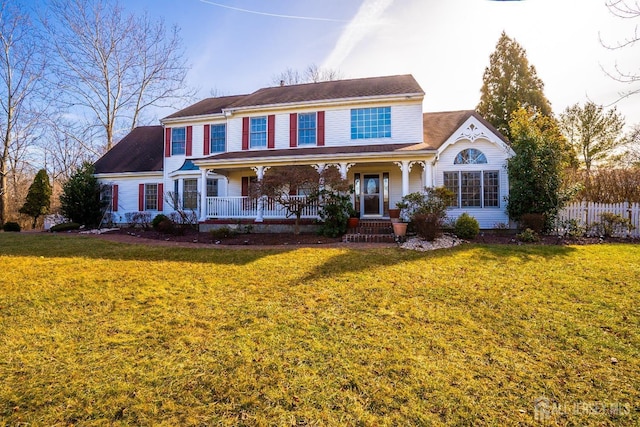 view of front of property with covered porch, a front yard, and fence